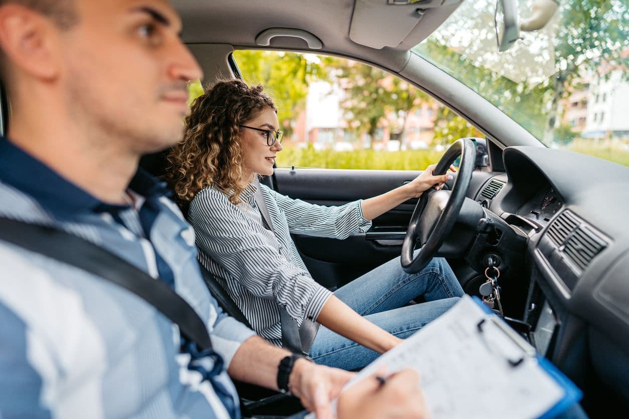un inspecteur du permis de conduire fait passer son examen de conduite à une jeune femme