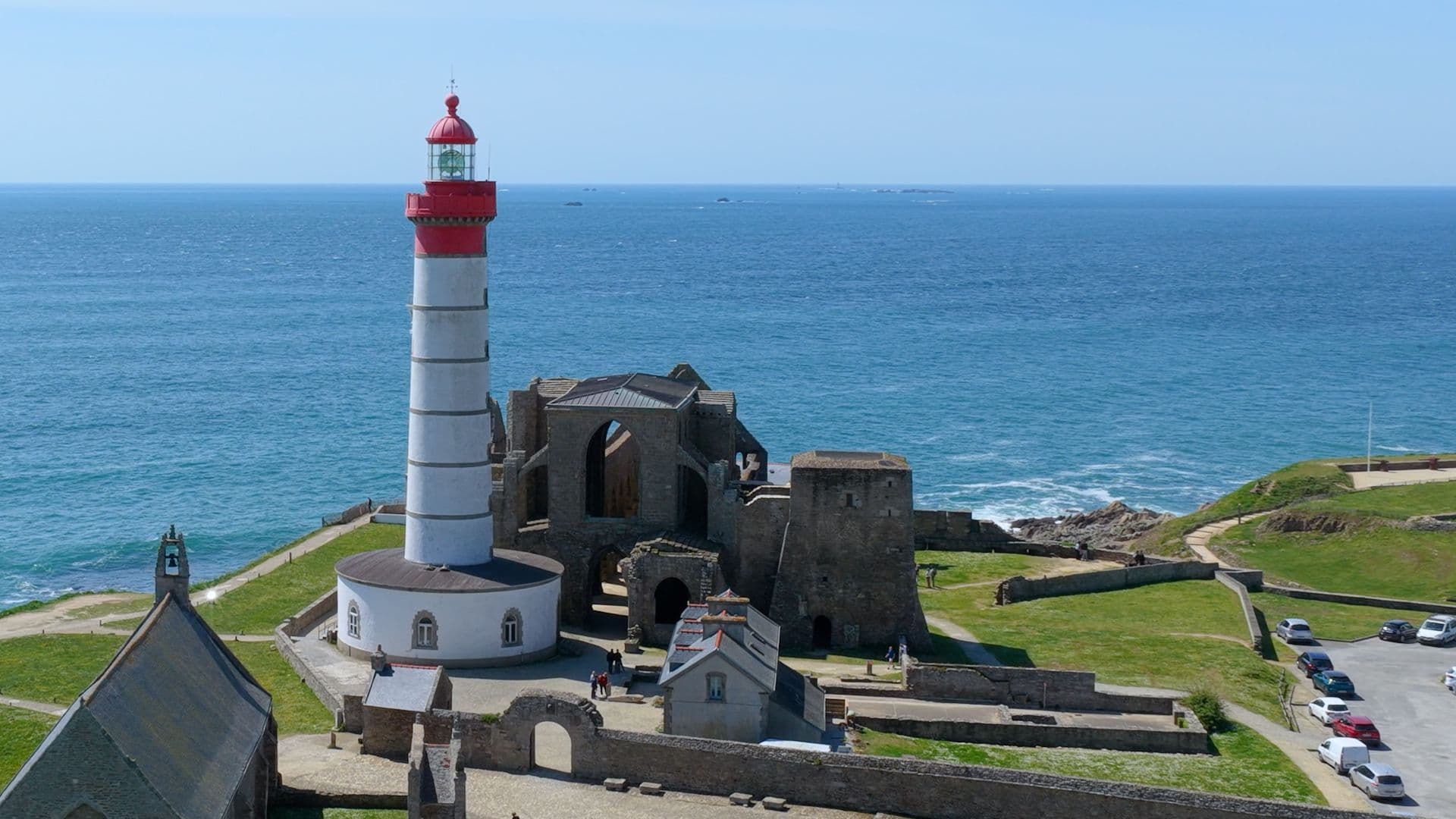 Phare rouge et blanc dominant des ruines côtières face à l’océan