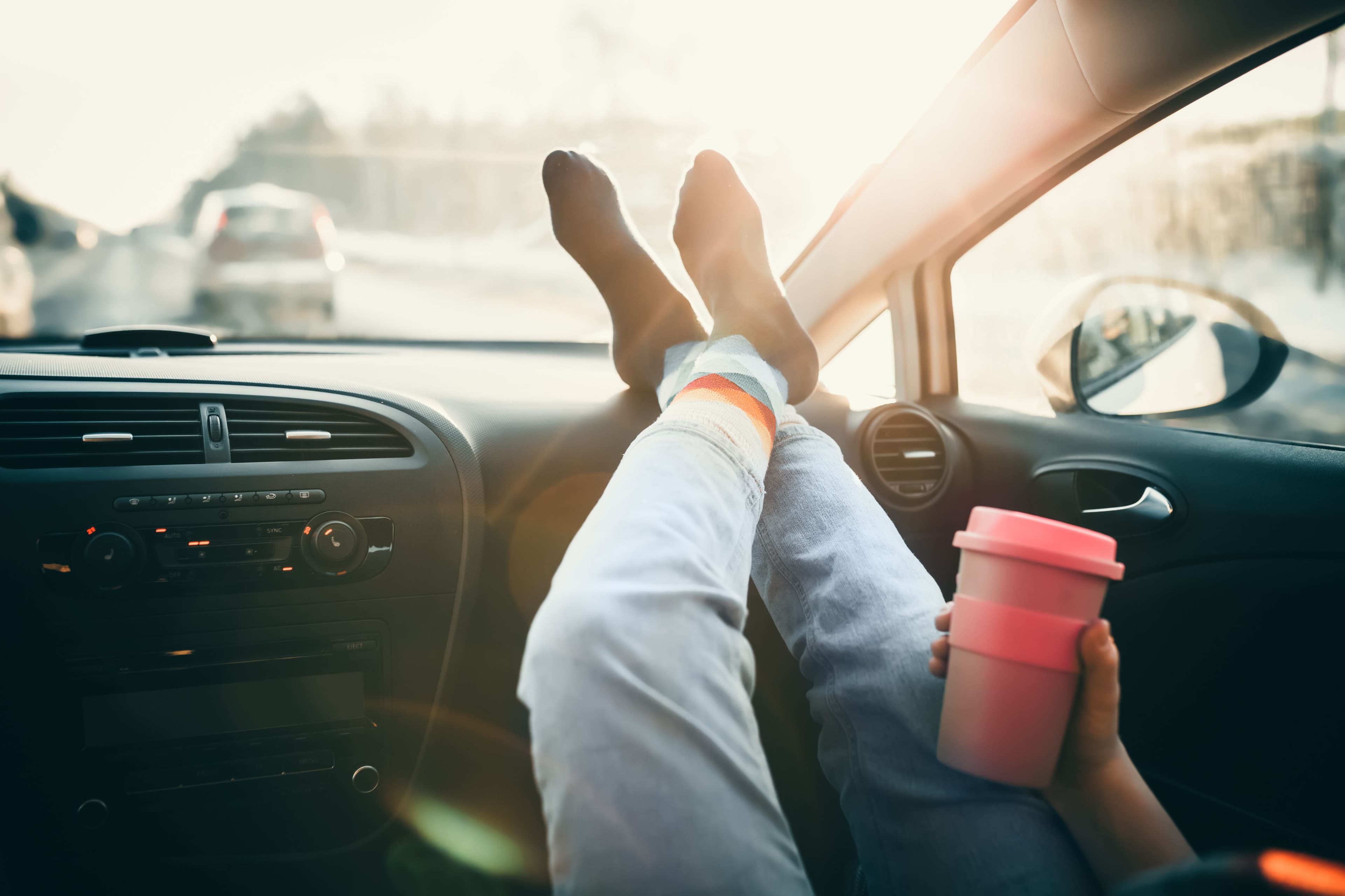Personne ayant posé ses pieds sur le tableau de bord d'une voiture.