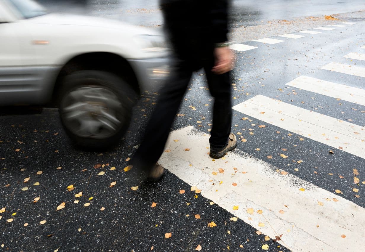 Piéton traversant un passage clouté devant une voiture en mouvement