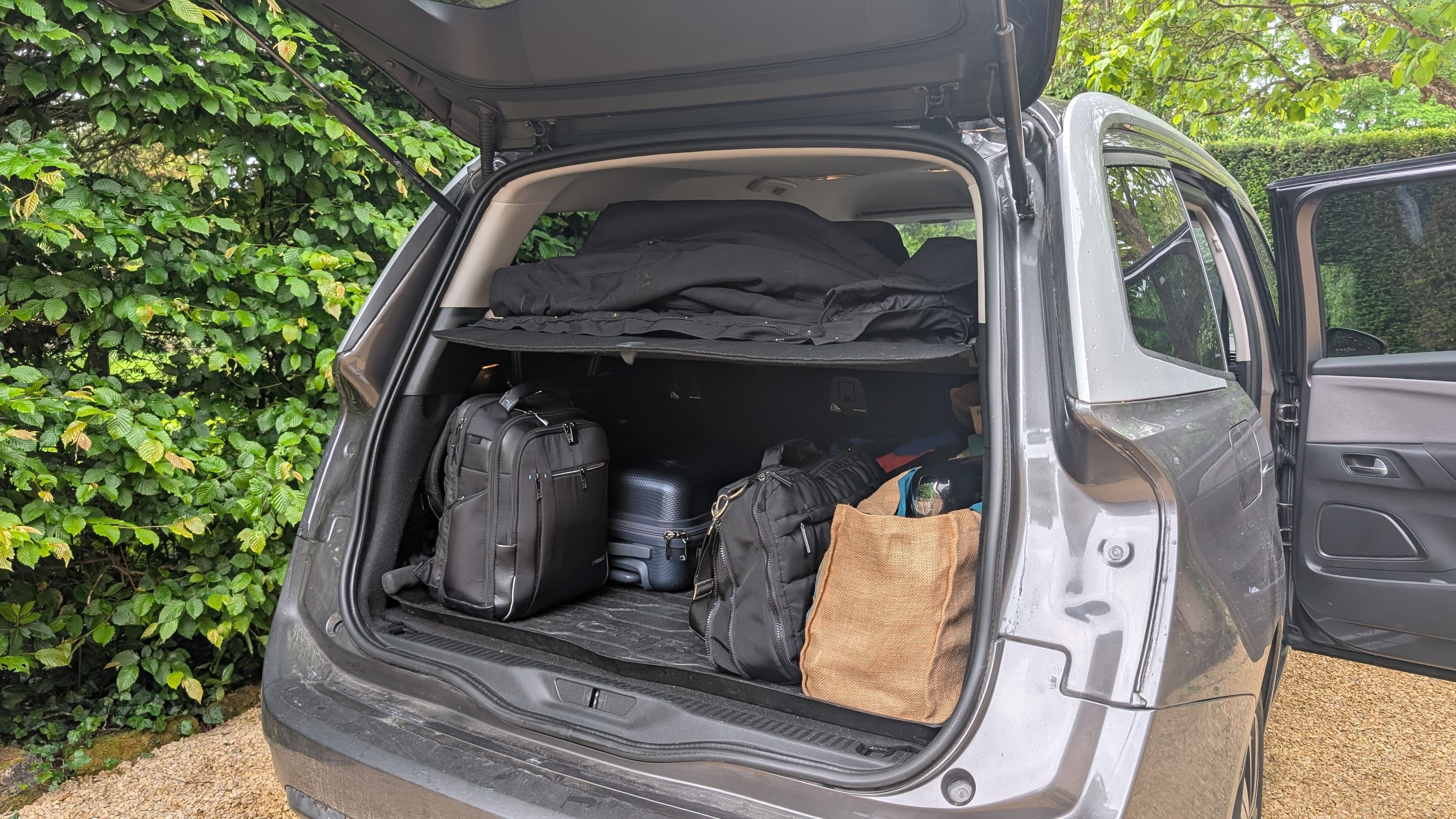 Coffre ouvert d’un SUV chargé de bagages et d’une étagère de rangement