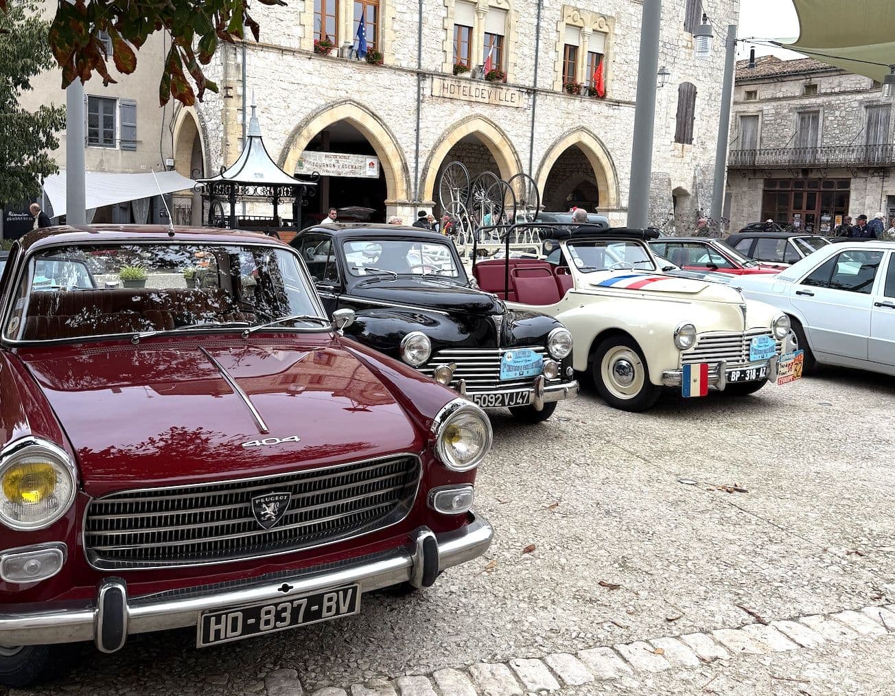 Voitures anciennes exposées sur une place de village