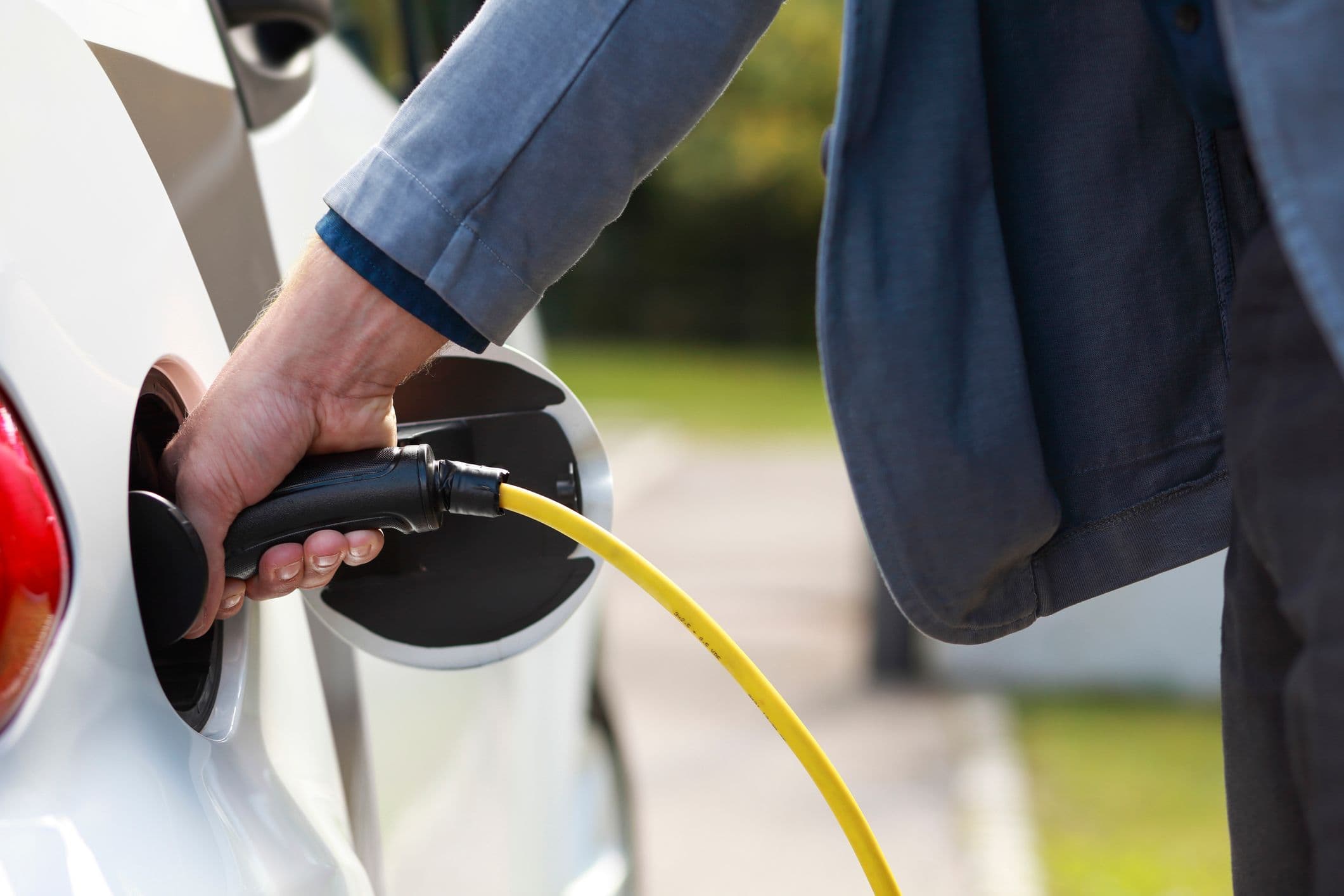 un homme branche une voiture électrique pour la recharger