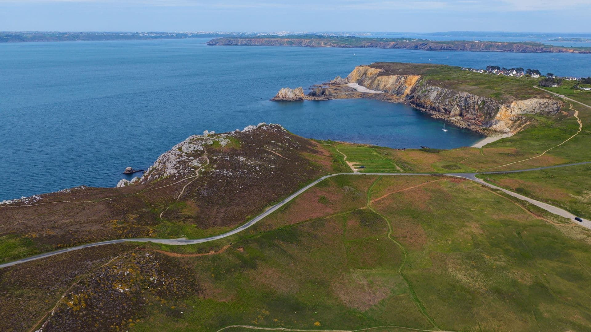 Côte rocheuse avec route sinueuse, crique et falaises surplombant la mer