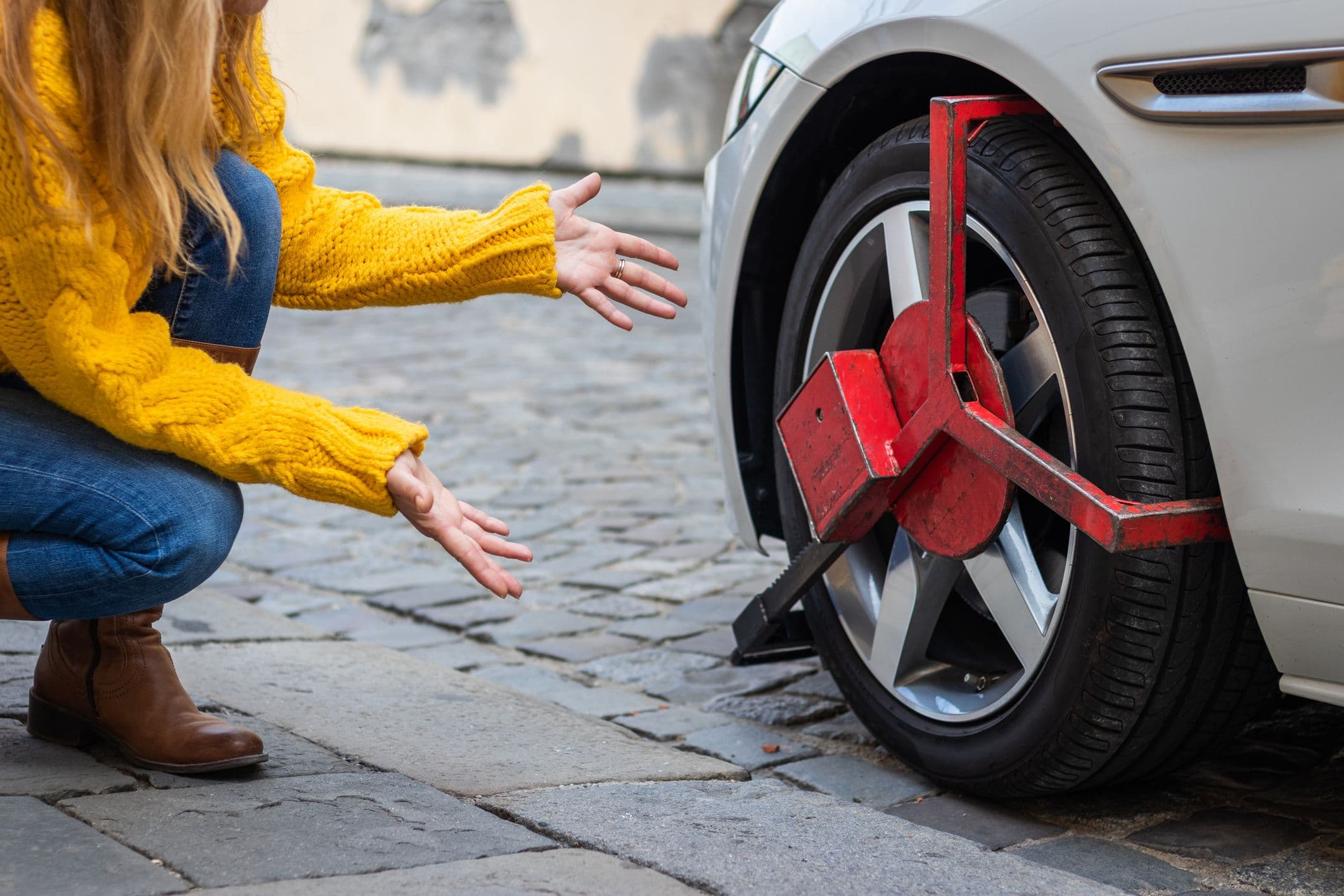 Femme constatant l'immobilisation de sa voiture par un sabot de Denver.