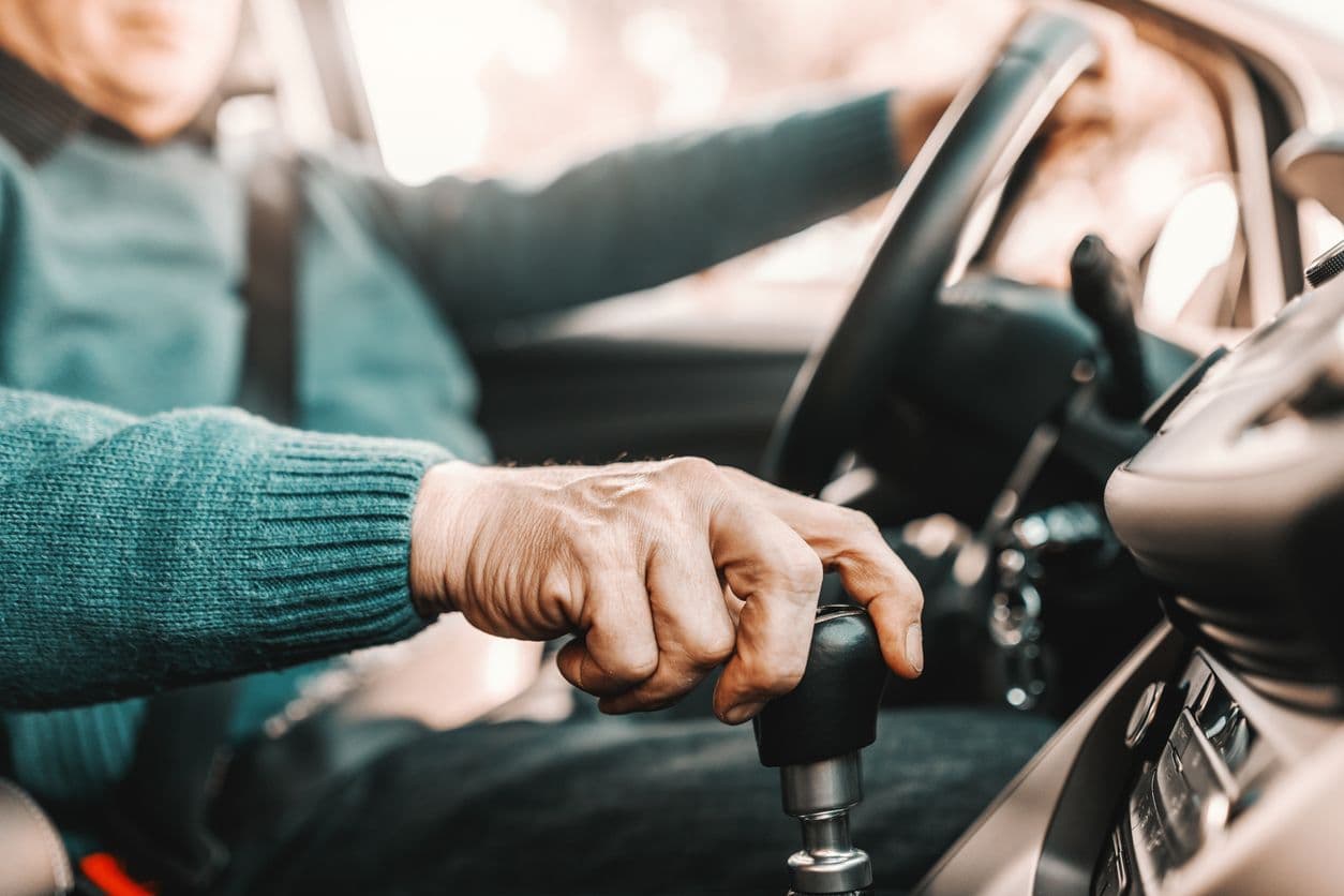 Main d'un conducteur posée sur le levier de vitesse d'une voiture.