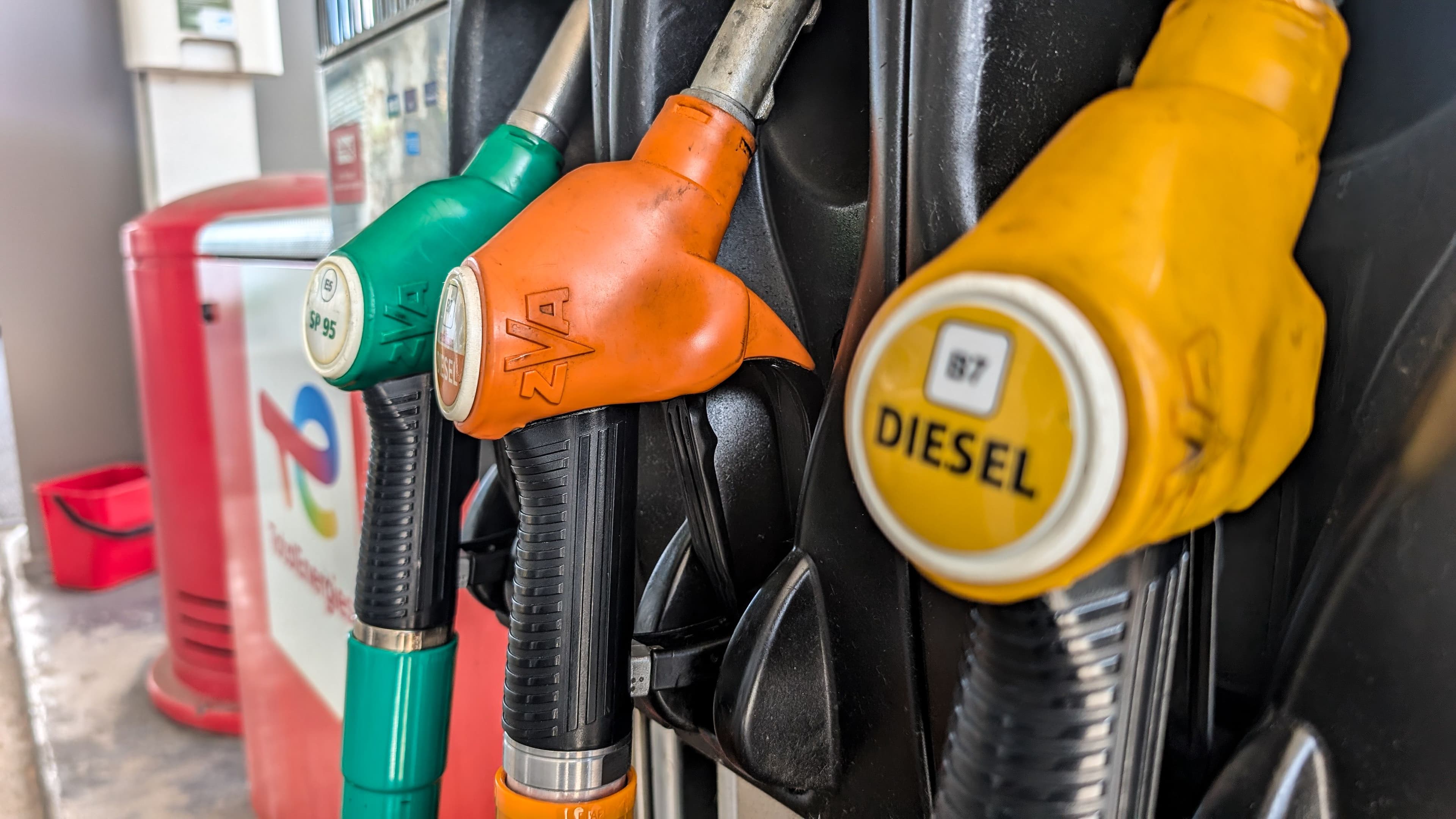 Zoom sur des pistolets de carburants dans une station-service Total Energies. Pompe à diesel jaune.