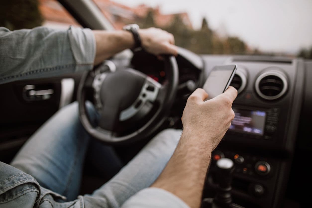 un homme consulte son smartphone alors qu'il est au volant d'une voiture