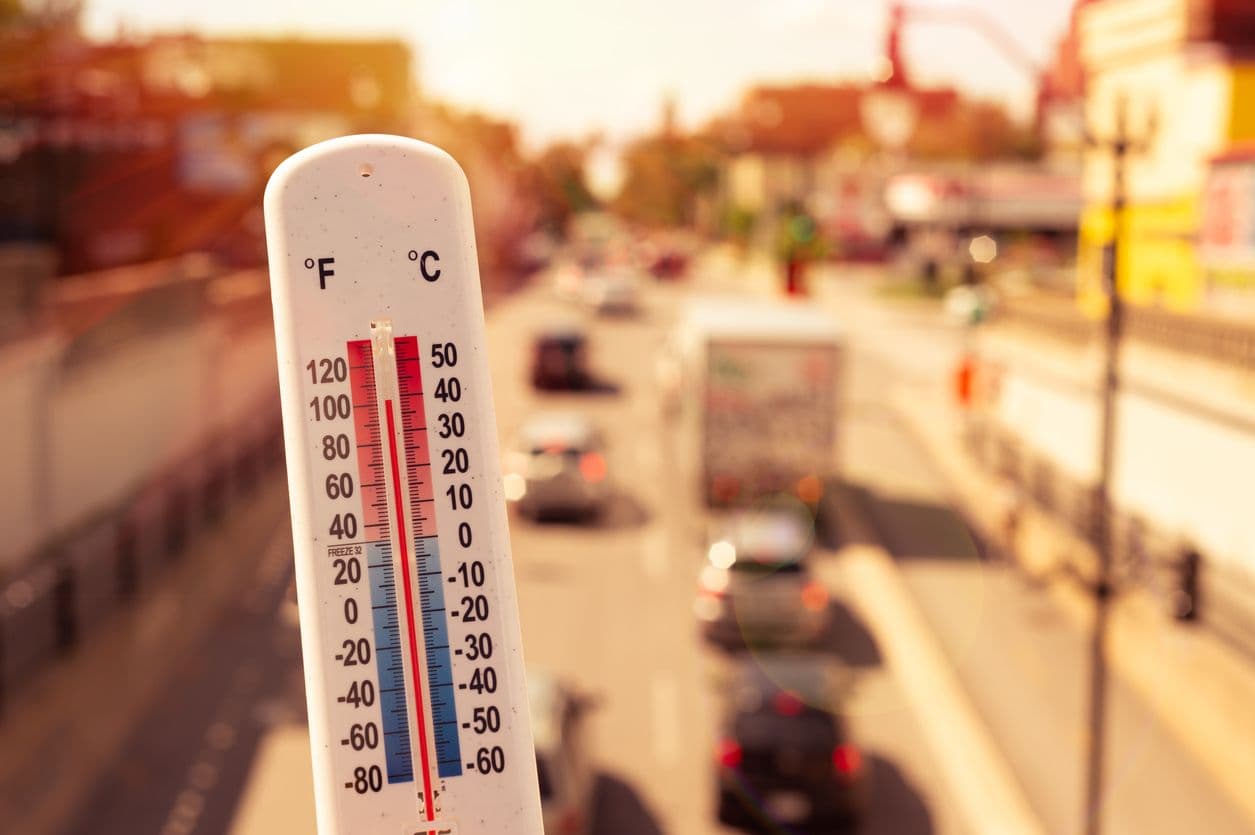 un thermomètre affichant 40°C devant une route avec de la circulation