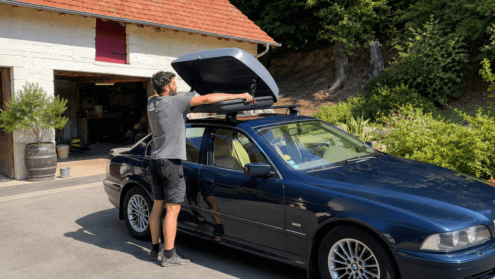 Un homme en train d'installer un coffre de toit sur sa voiture.