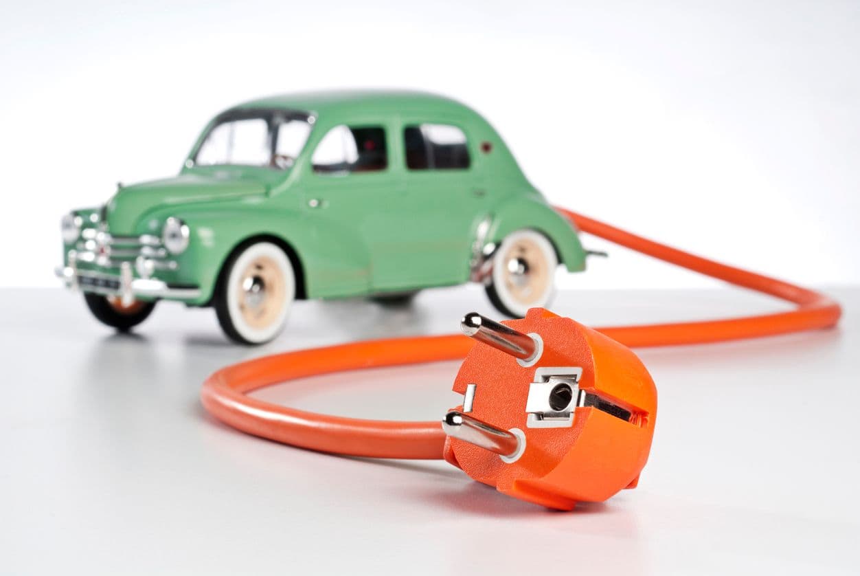 Une vieille voiture verte en jouet, avec un fil orange électrique