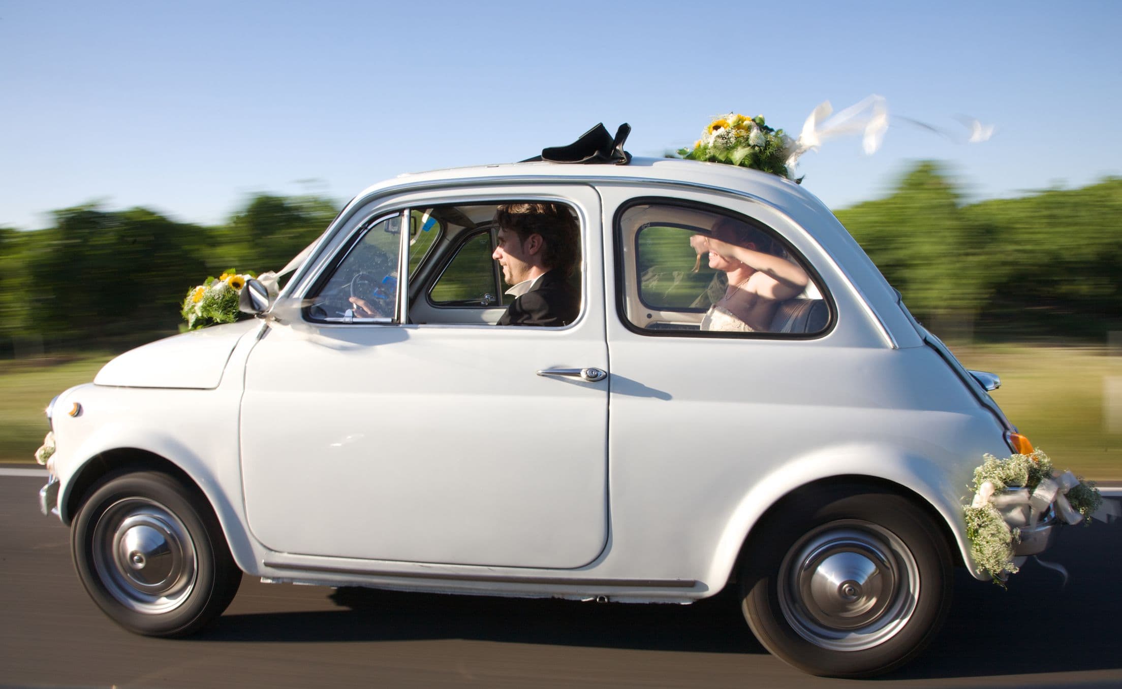Une voiture ancienne décorée transportant des jeunes mariés.