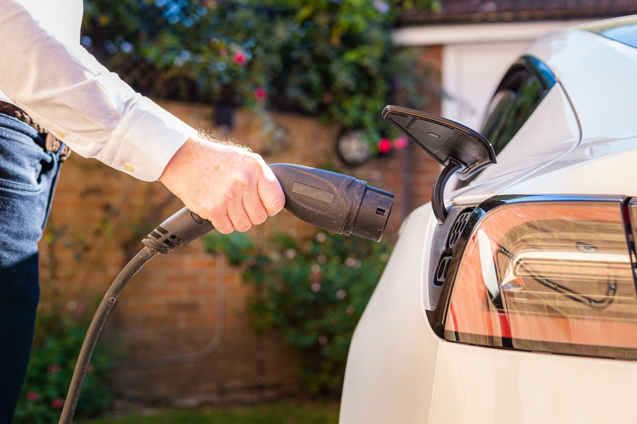 un homme branche une voiture électrique pour la recharger