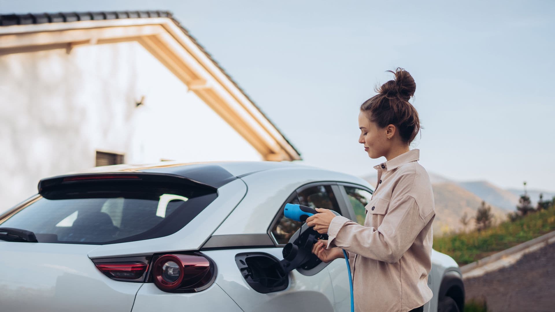 Une jeune femme qui charge sa voiture électrique pour la première fois afin de mettre en avant notre quiz sur les choses essentielles à savoir sur les véhicules électriques