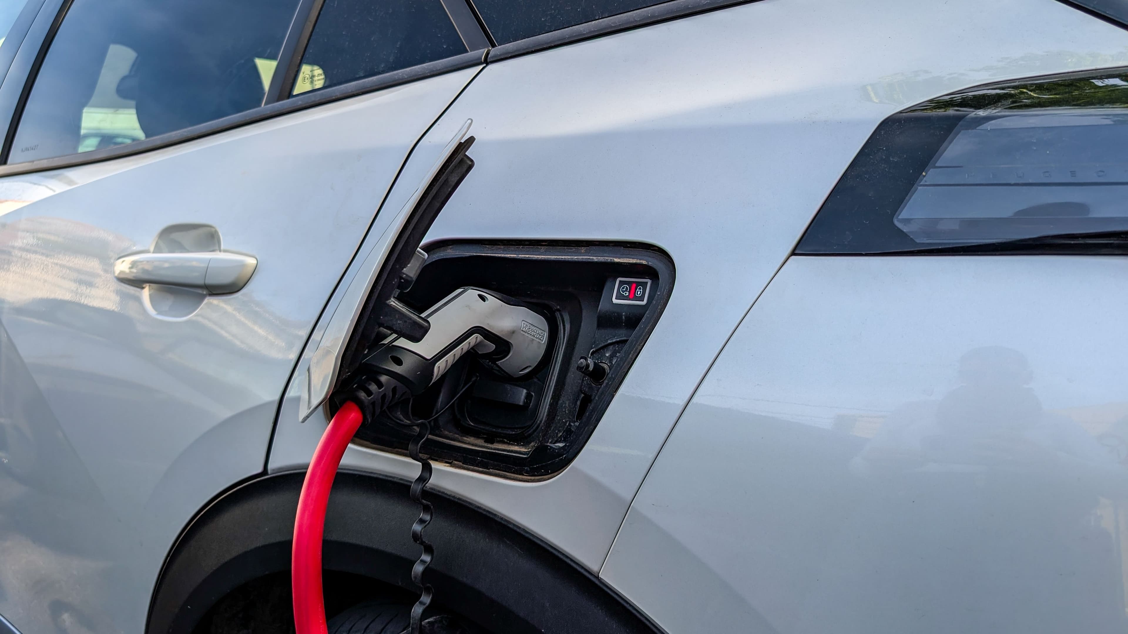 Une voiture électrique blanche branchée, en train de se recharger.