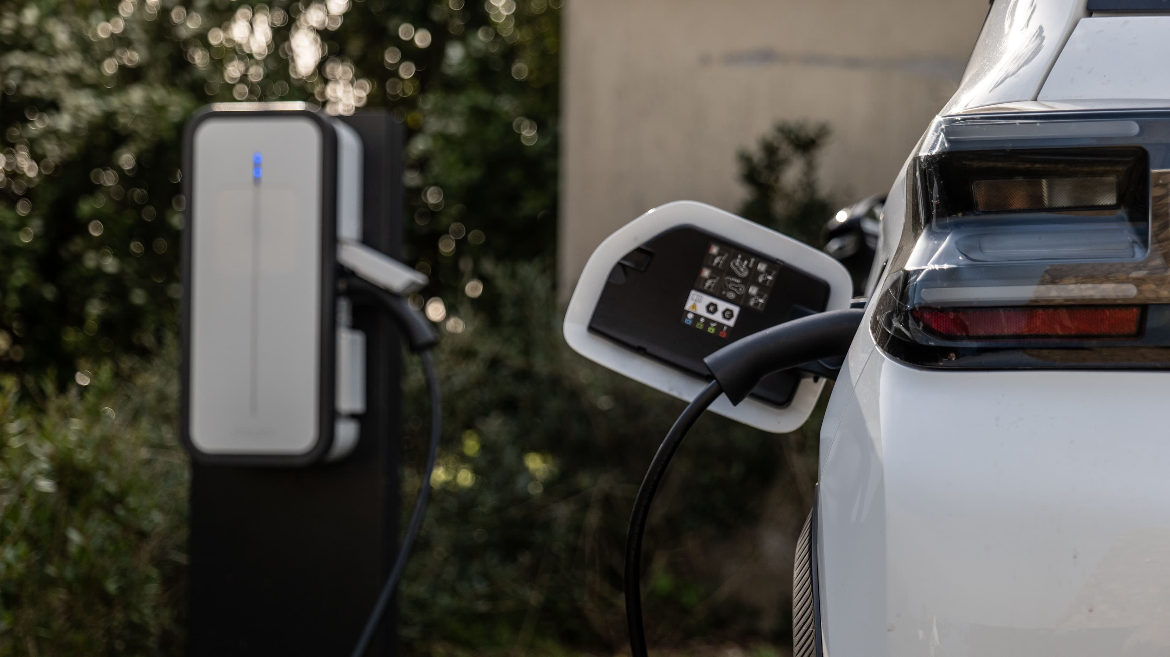 Une voiture électrique blanche en charge à une borne extérieure