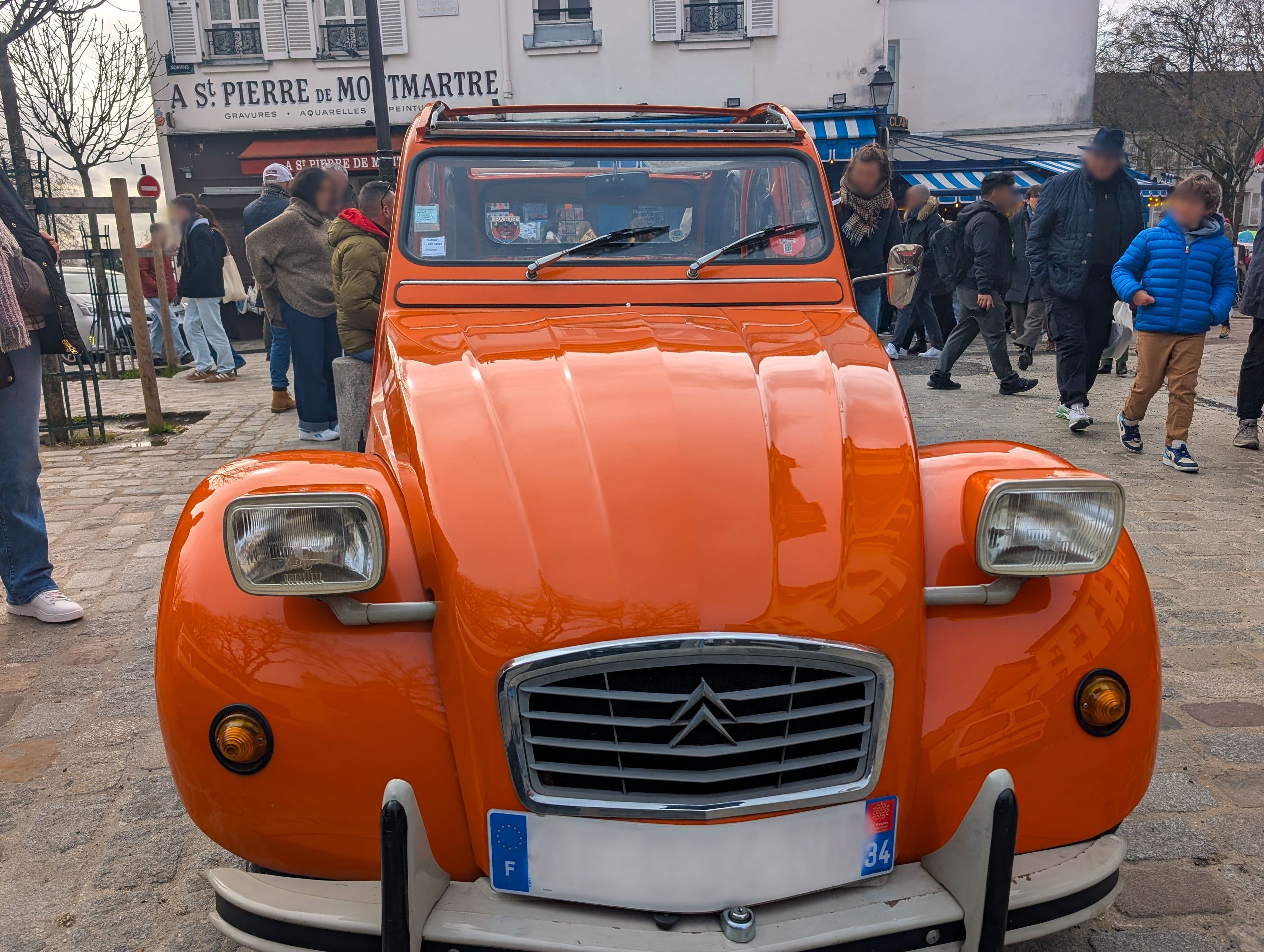 Une Citroën 2CV dans les rues de Montmartre à Paris, qui attire les regards des passants