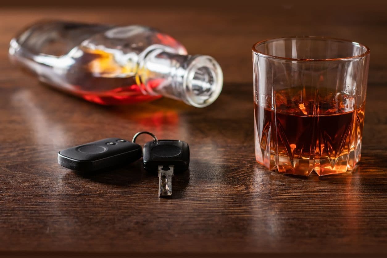 Un verre d'alcool posé sur une table à côté d'un trousseau de clés de voiture.