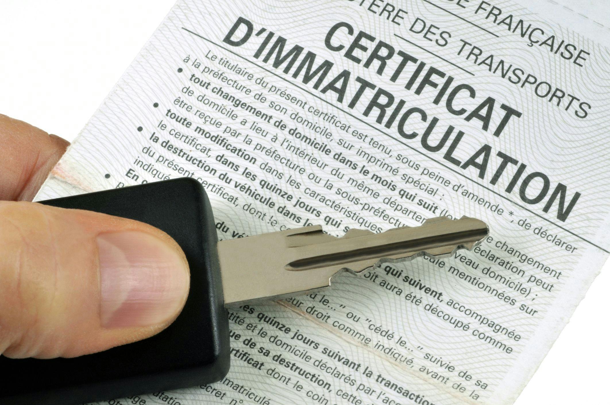 Photo d'une clé avec le certificat d'immatriculation d'un véhicule.