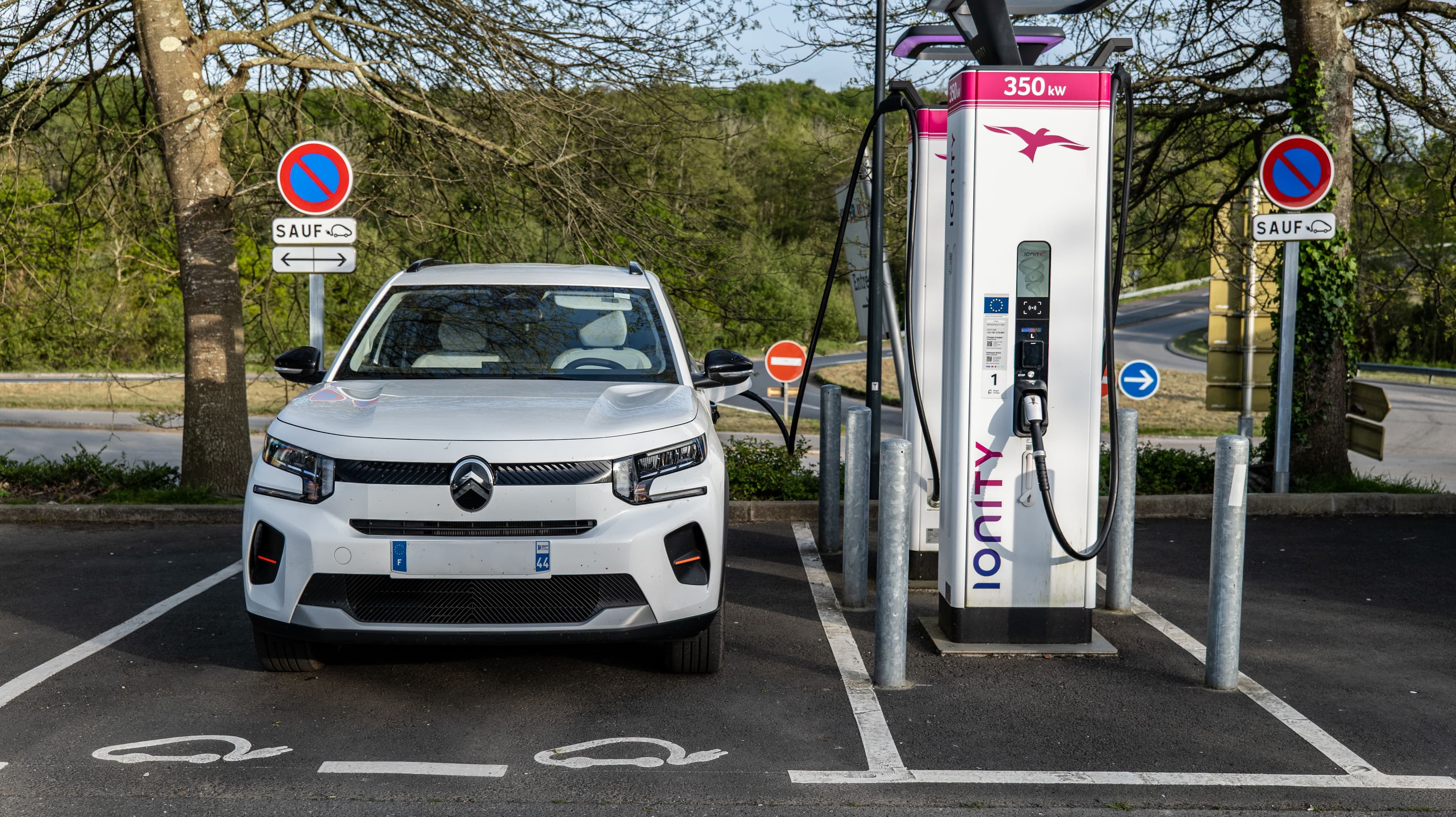 Une voiture électrique blanche branchée sur une borne de recharge ultra rapide de 350 kW marque IOnity