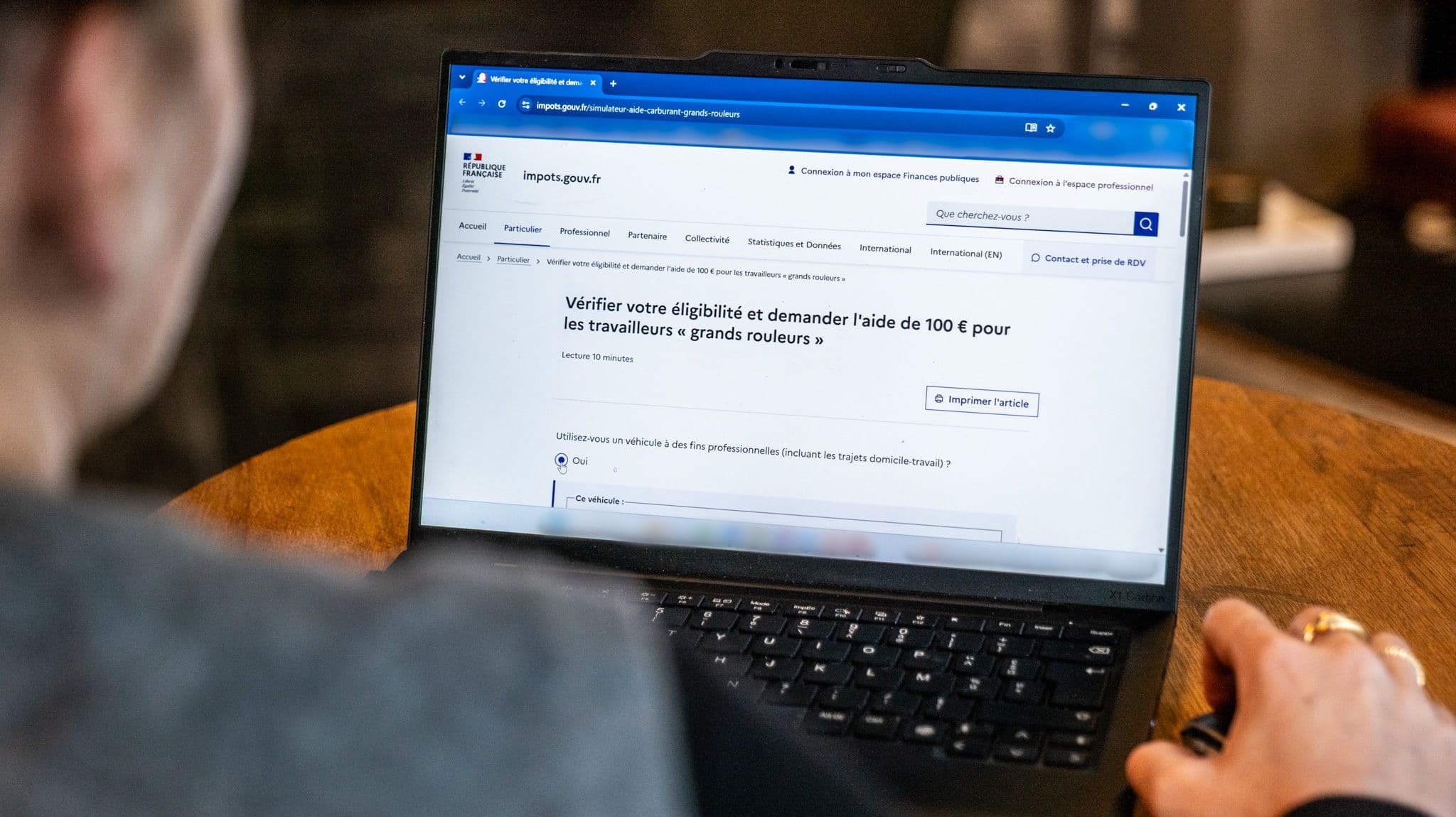 Un personne sur son ordinateur portable affichant le simulateur du site impots.gouv.fr sur l’aide carburant de 100 euros
