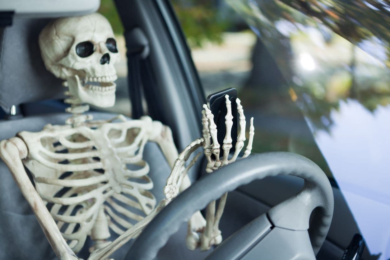 Un squelette au téléphone au volant d'une voiture.