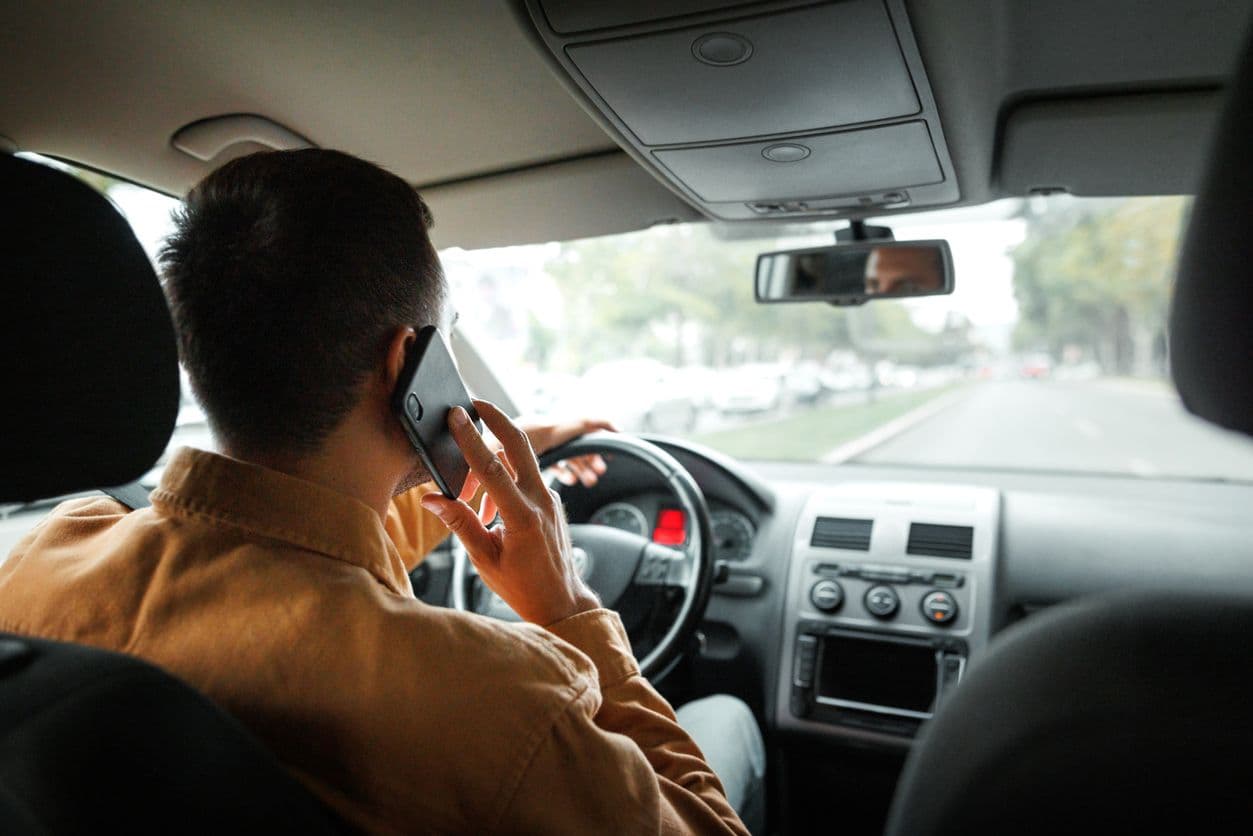 Un homme téléphone au volant de sa voiture.