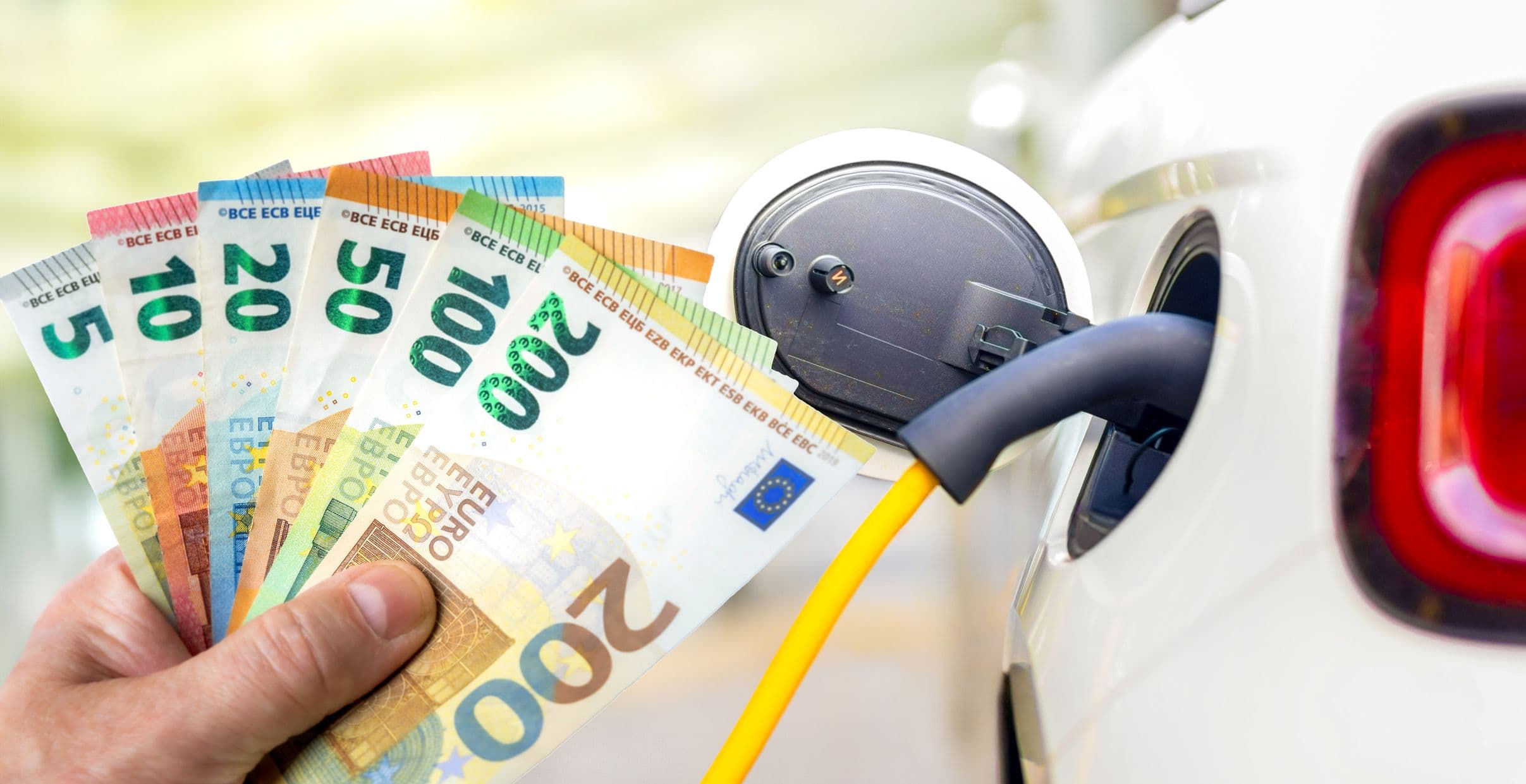 Un automobiliste tient dans sa main 300 euros en billets devant sa voiture électrique en charge