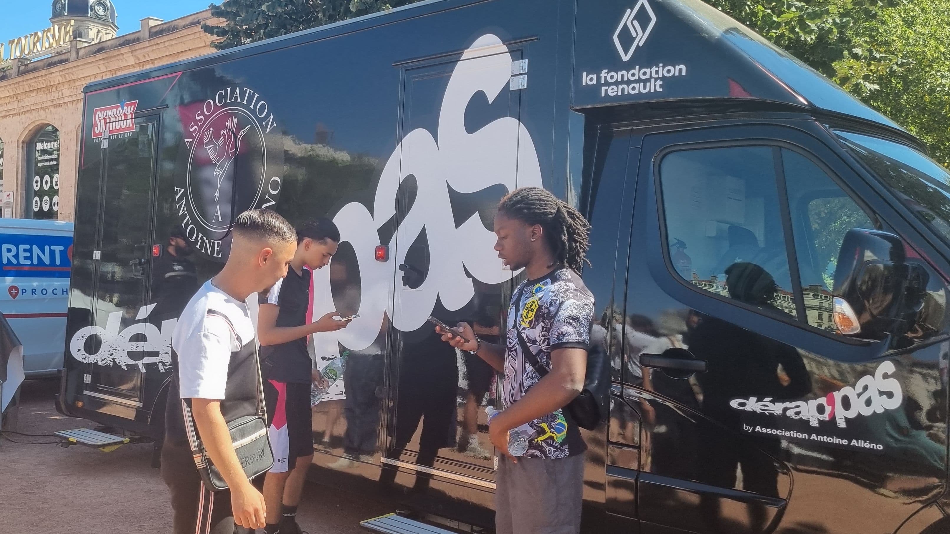 Trois jeunes répètent leurs textes de rap devant un camion studio d'enregistrement