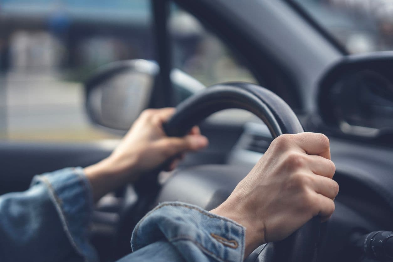 Des mains sur un volant de voiture