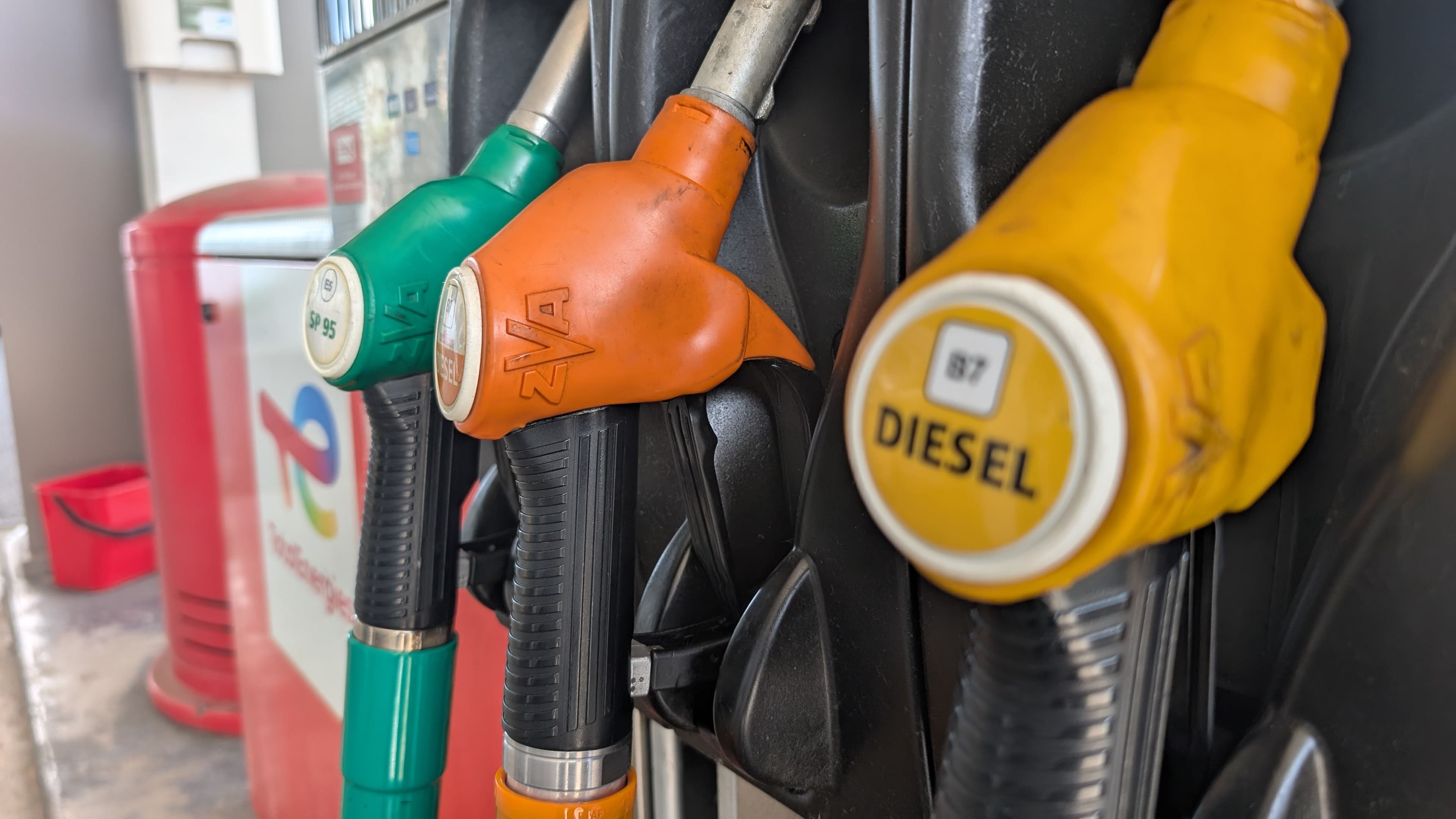 Gros plan sur des pistolets de distribution de carburant (Diesel B7 et Sans Plomb 95) dans une station-service TotalEnergies.