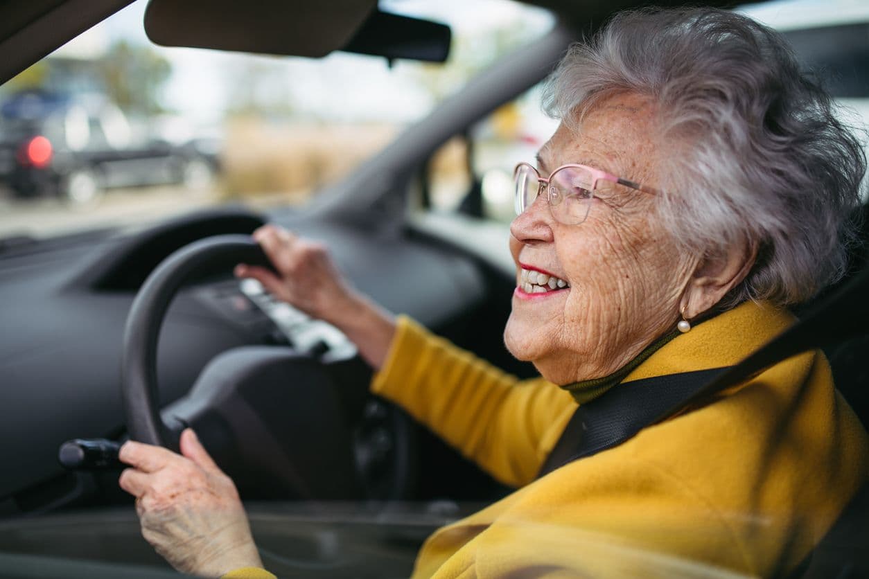 Femme âgée heureuse conduisant une voiture seule, profitant d’une balade en voiture. Conduite sécuritaire pour les personnes âgées, sécurité des conducteurs âgés.