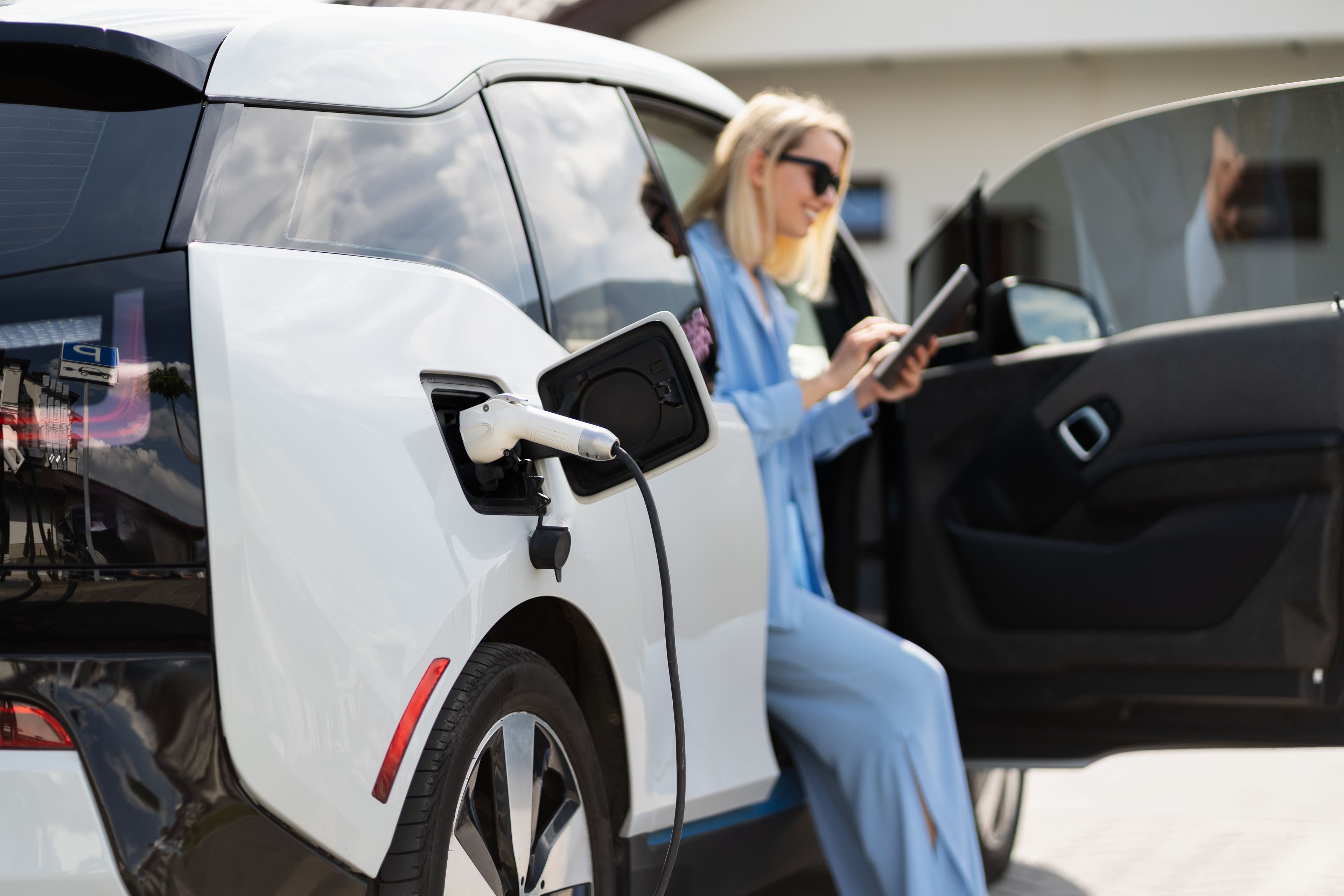 Une femme attend que sa voiture électrique se recharge